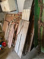 Photo showing 6 vintage sleds including 5 wooden sleds and 1 wooden toboggan leaning against a wall in a garage.