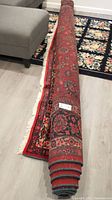 Partially unrolled rug on floor showing overall pattern and backing edge