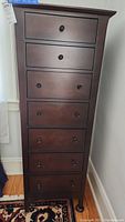 Front view of tall wooden lingerie dresser showing seven drawers with wooden knobs.