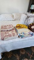 Pottery Barn quilt with matching shams seen on bed, folded quilts and shams stacked on top, shows variety of textures and patterns.