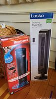 Photo showing the boxed Lasko oscillating tower fan and Honeywell ceramic heater side by side.