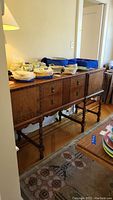 Front view of wooden buffet credenza showing decorative doors, drawers with bubble trim, and some items on top (not included).