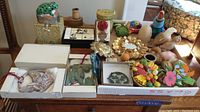 Wide shot of entire lot showing all items on table including frog trinket box, boxed ornaments, framed prints, magnets, and decorative curios.