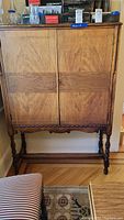 Full view of vintage wooden cabinet showing front doors, legs, and overall condition.
