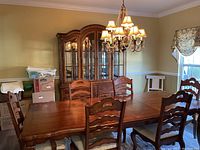 Front view of cherry dining table set with six chairs in dining room, china cabinet in background