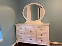 Front view of white dresser with oval mirror and detailed central drawer