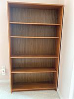 Front view of full 5-shelf wooden bookcase showing wood grain back panel and shelves