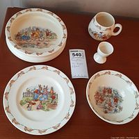 Full set of five Bunnykins rabbit-themed child dishware pieces on wooden table.