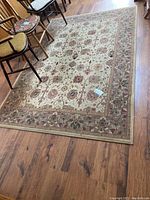 Full view of the rectangular Jordan carpet on a wooden floor with chairs around.
