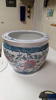 Side view of the round ceramic planter pot with blue and red oriental style floral patterns on white background.