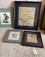 Overall view showing all four framed embroidery pieces on carpeted floor.