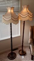 Pair of lamps side by side in front of window showing shades and bases