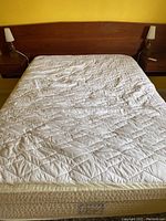 Front view of wood veneer headboard mounted behind mattress and box spring