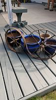 Blue ceramic planters and vintage metal wheels on grey wooden deck, showing condition and size relation