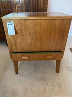 Front view of the wood sewing cabinet showing its smooth wood finish and angled legs