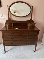 Front view of solid wood dresser with riser shelf and oval mirror showing six main drawers and two small riser drawers