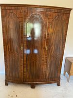 Front view showing three-door wood veneer exterior and brass hardware