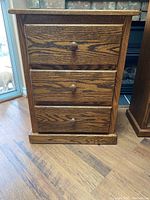 Front view of a wood 3 drawer cabinet with round wooden knobs