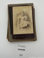 Stack of vintage black and white CDV photographs depicting a young child sitting in a chair, with photographer's mark 'McDougall'