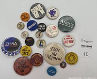Photo showing a collection of 21 vintage pinback buttons with varied slogans, logos, and imagery from the 1970s and 1980s.
