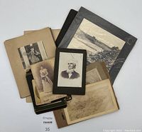 Top view of assorted mounted vintage photos including a portrait, landscape, snowy scene, and old church