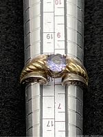 Close-up photo of sterling silver ring on ring sizer showing lilac gemstone and twisted rope bezel design.