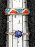 Two sterling rings side by side on ring sizer: a blue stone ring size 6 and a Navajo coral turquoise inlay band size 4.5