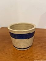 Front view of ceramic pot showing beige body with two dark blue bands.