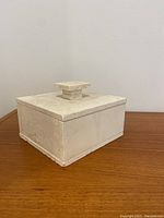 Front angle of vintage travertine box with lid on, showing textured stone surface and square handle