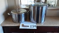 Wide shot showing the large stockpot with glass lid and the smaller stainless steel pot with lid next to it.
