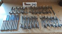 Full set laid out on countertop showing all pieces including knives, forks, spoons, and meat fork