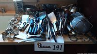 Wide view showing large assortment of kitchen utensils including graters, cutters, peelers, whisks, spatulas, and measuring spoons arranged on a counter.