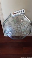 Octagonal iridescent stained glass panel featuring iris flower design, standing upright near a wall and displaying the sign with auction lot number.