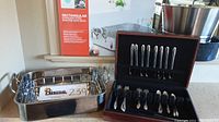 Rectangular stainless steel roaster with cooking rack and Community silverplate flatware set in open wooden box