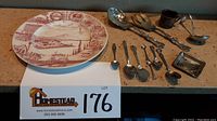 Full lot view with all items including souvenir plate, two serving utensils, ladle, ashtray, mug, and spoons arranged on countertop