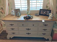 Front view of wood dresser showing painted body, wooden top, and six drawers with metal handles