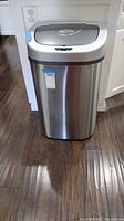 Front view of the Ninestars metal trash bin with closed lid and sensor on front.