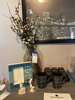 Full lot view showing coffee mugs, picture frame, vase with flowers, checkers set, and figurines