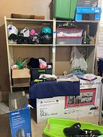 Photo of beige metal shelving unit with various storage items on shelves, showing structure and condition.