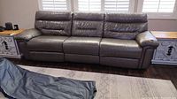 Front view of the three-seat grey leather reclining couch showing overall condition and seating alignment