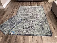 One large blue and grey rectangular rug on wood floor next to a smaller matching rug.