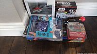 Boxed Hover Star RC helicopters and Star Wars Micro Machines toys on floor against white wall.