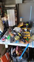 Photo of assorted tools, hardware, adhesives, a bag of cement, and other items laid out on a table.