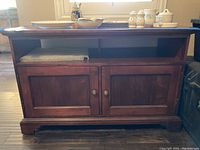 Front view of dark wood TV cabinet with two doors and open shelf