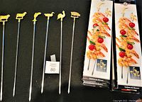 Photo displaying 6 barbecue skewers with farm animal shaped handles, including a cow, sheep, rooster, turkey, and more, alongside original boxed packaging.