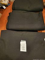 Three folded pieces of black felt fabric stacked, large pieces for crafting or table cover use.