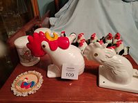 Photo showing the ceramic rooster and hen heads along with multiple ceramic chicken salt and pepper shakers arranged on a wooden surface.
