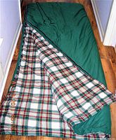 Sleeping bag with green exterior partially unzipped to show plaid interior lining
