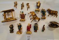Overview photo showing all 12 hand-carved Japanese Netsuke figurines including human characters, animals, and a miniature hut scene.