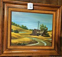 Close-up of the framed country scene showing the barn, windmill, and country road details in a wooden carved frame.